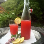 Fotos Himbeerlimonade - In einer schönen Glasflasche und in einem Glas dekoriert mit Minze, Zitronen und gefrorenen Himbeeren